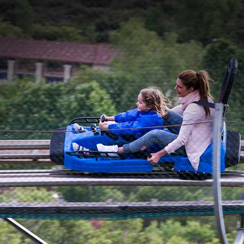 Mère et fille sur l'une des luges de l'attraction Bobsleigh glissant sur ses rails.