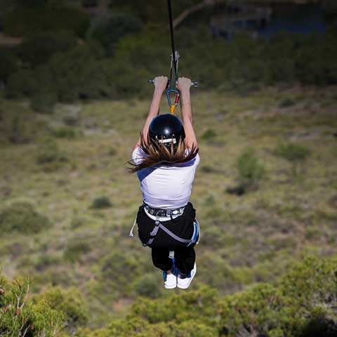 Woman jumping down the zip line on her back.