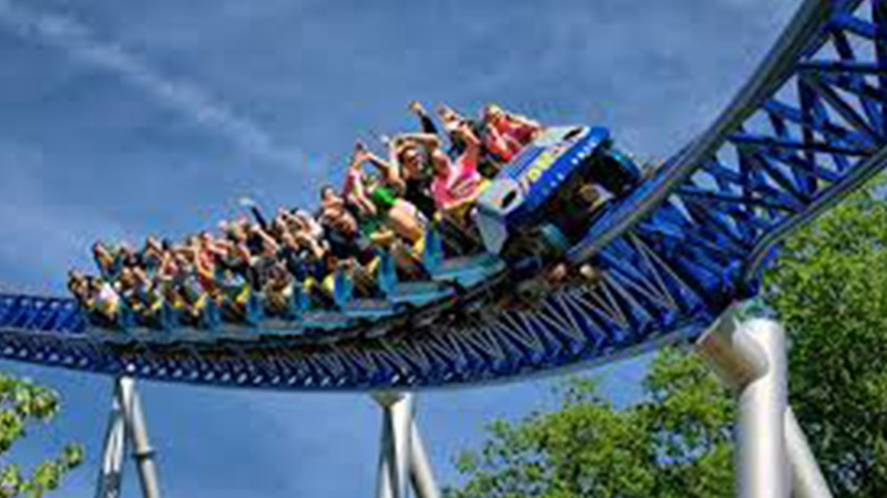 Image of a roller coaster in motion, with people riding on it.