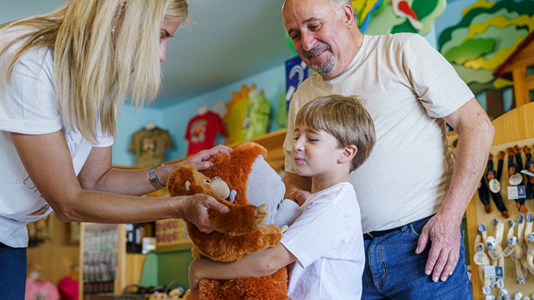 Grandfather, mother and child in the Sendaviva store. The child hugging the stuffed animals.