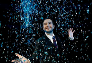 Photo of magician Jorge Blass, surrounded by confetti.