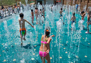 Enfants jouant dans l&#039;attraction aquatique &quot;Le Labyrinthe&quot;, où des jets d&#039;eau sortent du sol.